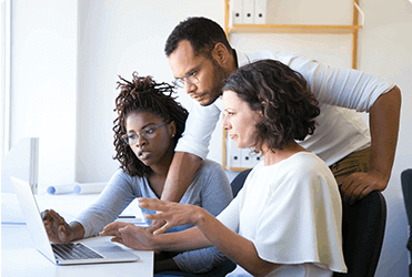 Group of 3 discussing in front of a laptop
